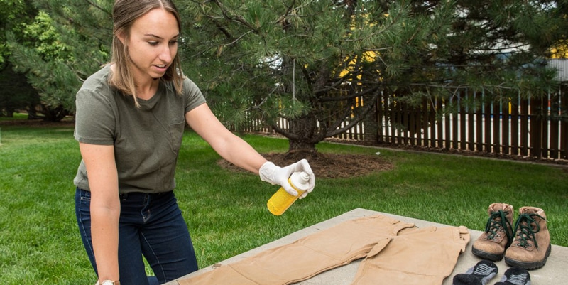 Protecting against mosquitoes Woman spraying clothing with permethrin