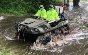 Staff driving through flooded waters in ATV.
